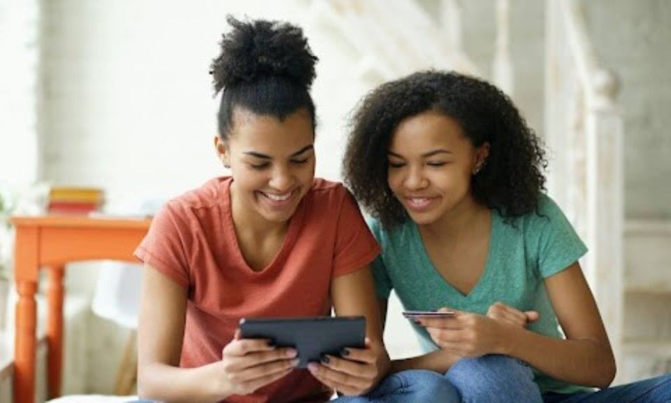 Two women shopping online with a tablet and credit card, illustrating what free shipping means for eCommerce customers and how it influences online buying behavior.